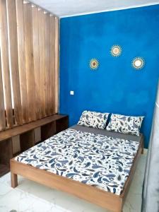 a bed in a room with a blue wall at Gêna house in Douala