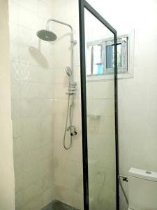 y baño con ducha y puerta de cristal. en Gêna house en Douala
