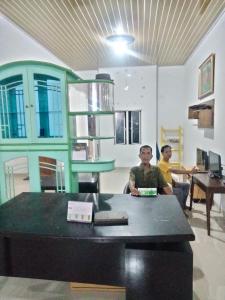 two men sitting at a table in a room at Domen homestay syariah krui 64 in Krui