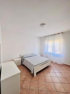 ein weißes Schlafzimmer mit einem Bett und einem Fenster in der Unterkunft CANNONHOUSE La Pavoncella Rosa in Bari Sardo