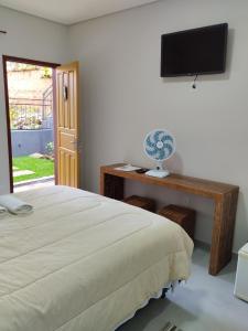 a bedroom with a bed and a television on a desk at Pouso Casa da Vovó in Tiradentes