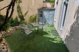 a patio with a table and chairs on the grass at Classé 4 étoiles - Cybèle - Centre ville 2 Chambres, cour privative et Garage in Vienne