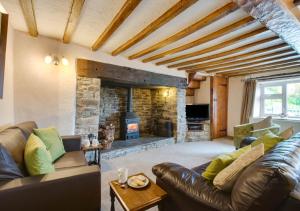 a living room with a leather couch and a stone fireplace at Caer Mynach Cottage in Maesmynis