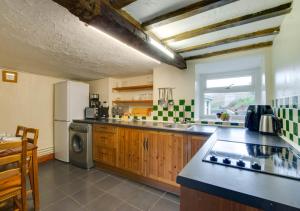 a kitchen with a sink and a refrigerator at Caer Mynach Cottage in Maesmynis