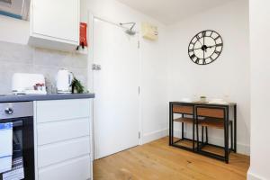 una cucina con armadi bianchi e un orologio sul muro di Central Buckingham Apartment #7 with Free Parking, Pool Table, Fast Wifi and Smart TV with Netflix by Yoko Property a Buckingham
