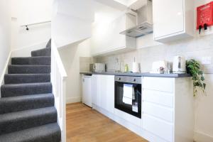 a kitchen with white cabinets and a staircase at Central Buckingham Apartment #7 with Free Parking, Pool Table, Fast Wifi and Smart TV with Netflix by Yoko Property in Buckingham
