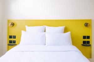 1 cama con almohadas blancas y cabecero amarillo en Le Lieu Dit, en Nantes