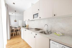 a white kitchen with a sink and a table at Líbere Ciudad Real in Ciudad Real