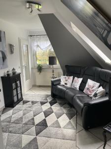 a living room with a black couch and a checkered floor at Maison Beaumont in Springe