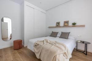 Un dormitorio blanco con una cama con una manta. en Líbere Ciudad Real, en Ciudad Real