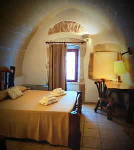 a bedroom with a bed and a desk and a window at Masseria Quis Ut Deus in Crispiano