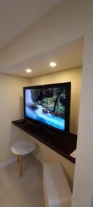 a flat screen tv on a wall with a stool at Recanto de Itaipava - casa com forno de pizza a lenha, churrasqueira, pet friendly, equipada para até 6 pessoas, em meio à Natureza e próxima ao centro do bairro in Araras Petropolis