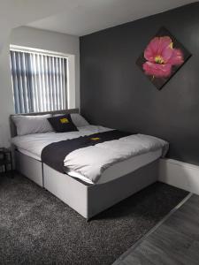 1 dormitorio con 1 cama con una flor en la pared en Black Ocean Holiday Apartments, en Blackpool