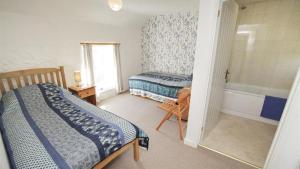 een slaapkamer met 2 bedden en een bad bij Frog Lane Cottages in Llanmadoc