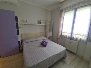 un osito de peluche púrpura sentado en una cama en un dormitorio en Sara by PortofinoVacanze, en Rapallo