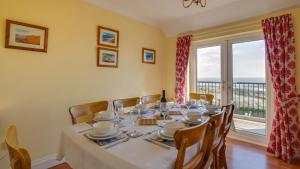 a dining room with a table and a large window at Fennel Cottage in Port-Eynon