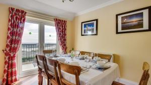 a dining room with a table and a large window at Malt Cottage in Port-Eynon