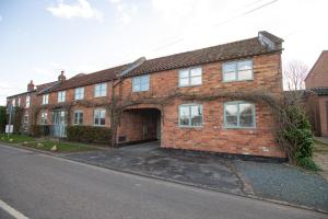 a brick house with an archway on a street at Pass the Keys Cosy Hideaway in the Countryside in Lincoln