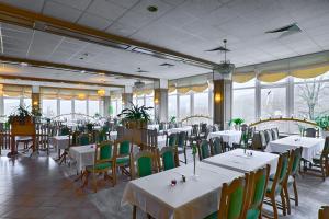 um restaurante com mesas e cadeiras brancas e janelas em Panorama Hotel Oberwiesenthal em Kurort Oberwiesenthal