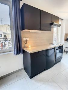 a kitchen with black cabinets and a large window at Appart Hyper Centre Tout Confort Wifi 4 Pers in Romilly-sur-Seine