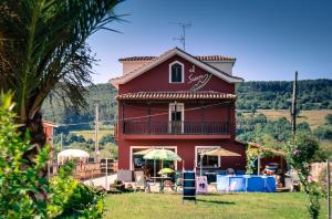 a red house with a balcony and a table and chairs at Hotel El Sueve in Colunga