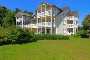 ein großes weißes Gebäude mit einem Hof davor in der Unterkunft Ferienwohnung im Dünenpark in Binz