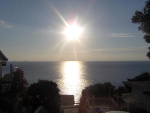 a view of the ocean with the sun in the sky at Apartments Jana in Primošten