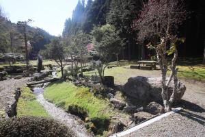 einen Garten mit Felsen und Bäumen und einem Bach in der Unterkunft 里山アウトドアフィールド・古民家コテージとろせ in Gujō