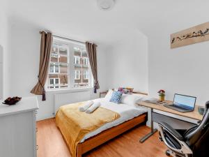 a bedroom with a bed and a desk with a laptop at Pass The Keys - Spacious Modern 2BR Flat for 6, 3min walk to Hammersmith Station in London