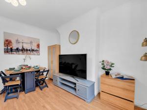 ein Wohnzimmer mit einem Tisch und einem großen TV in der Unterkunft Pass The Keys - Spacious Modern 2BR Flat for 6, 3min walk to Hammersmith Station in London