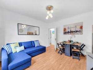 a living room with a blue couch and a table at Pass The Keys - Spacious Modern 2BR Flat for 6, 3min walk to Hammersmith Station in London