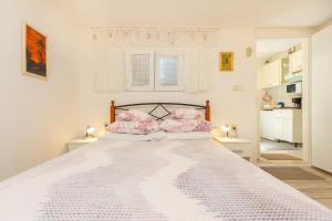 a white bedroom with a large bed with pink pillows at Studio Ibis in Dubrovnik