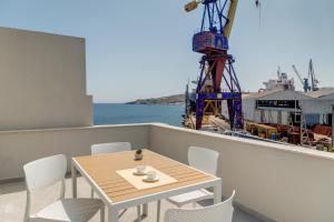 a table and chairs on a balcony with a ship at Marion Suite in Ermoupoli