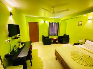 a bedroom with green walls and a bed and a desk at Banabani Resort in Srī Niketan