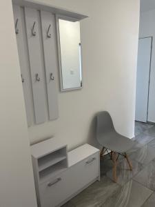 a white bathroom with a chair and a mirror at Horizont-Szilvás Apartman in Komló