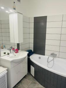 a bathroom with a tub and a sink and a bath tub at Horizont-Szilvás Apartman in Komló