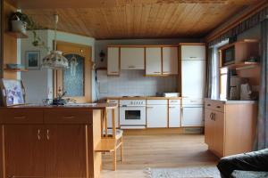 a kitchen with white cabinets and a wooden floor at Lassacher Biobauernhof in Mariapfarr