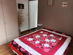 Schlafzimmer mit einem Bett mit einer roten und weißen Decke in der Unterkunft Vaiana in Beauvoir-sur-Mer
