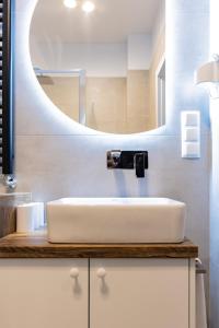 W łazience znajduje się biała umywalka i lustro. w obiekcie Apartamenty Kamienica Gwiazda w mieście Krynica Zdrój