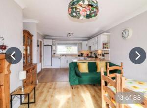Rossgier bungalow في Lifford: غرفة معيشة مع أريكة خضراء ومطبخ
