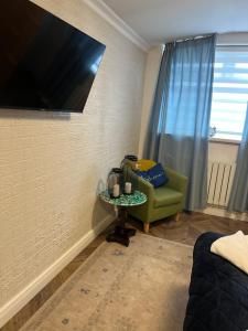 a living room with a tv and a green chair at Studio Flat in Wythenshawe