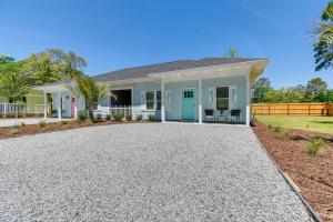 uma casa com uma entrada de cascalho em frente em Charming Ocean Isle Beach Home about 1 Mi to Beach! em Ocean Isle Beach