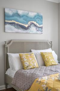 a bed with white pillows and a painting on the wall at Delightful 3 Bed House by Canary Wharf in London