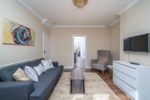 a living room with a couch and a tv at Delightful 3 Bed House by Canary Wharf in London