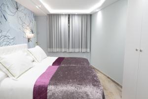 1 dormitorio con 1 cama con manta morada y blanca en THE MIRROR & SPA by Elegant Residences en Ransol