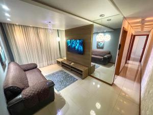 uma sala de estar com um sofá e uma televisão de ecrã plano em Apartamento c/estacionamento, próximo ao Shopping em Vila Velha