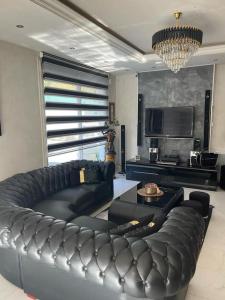 sala de estar con sofá de cuero negro en Olympic site Elancourt period Whole house en Élancourt