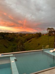 une piscine avec vue sur le coucher du soleil en arrière-plan dans l'établissement Eco Hotel La Colina Mirador, à Quimbaya