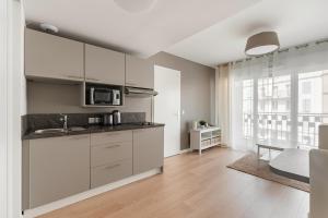 a kitchen with white cabinets and a large window at OVELIA Poissy - Les Romantiques in Poissy