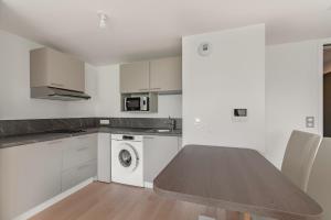 a white kitchen with a table and a microwave at OVELIA Poissy - Les Romantiques in Poissy